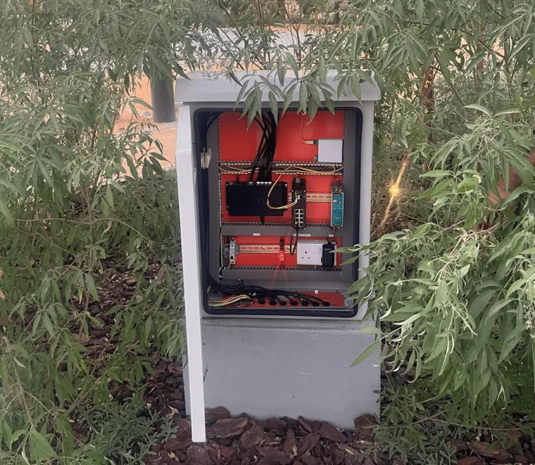 打开的路边控制柜，红色安装底板上装有导轨式控制器与接线端子，下方线缆整齐排布