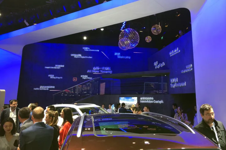 参观者围在车顶四周，蓝色墙面与镜面球在 Innovation Cockpit 屏幕后方泛光