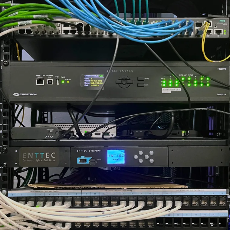 Equipment rack with network patch panels and coiled blue and green cables above a rack mounted ENTTEC S-Play
