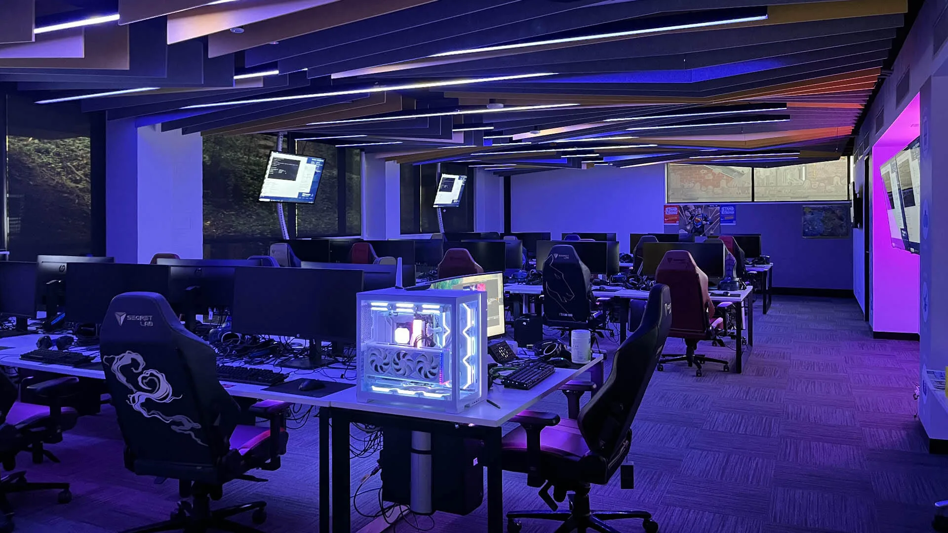 The VR room at Ballarat Tech School lit purple and blue, angled ceiling battens glowing above rows of gaming desks and chairs