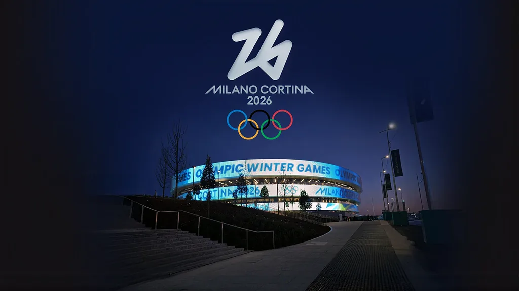 The arena lit blue at night, its façade running full-surface text