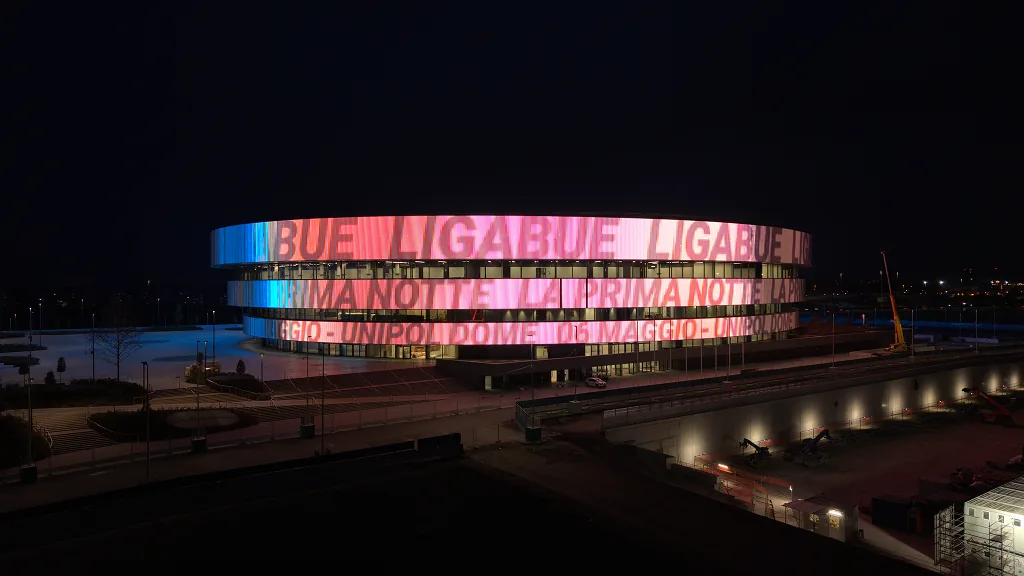 The façade in pink and blue promoting a concert at the UNIPOL Dome