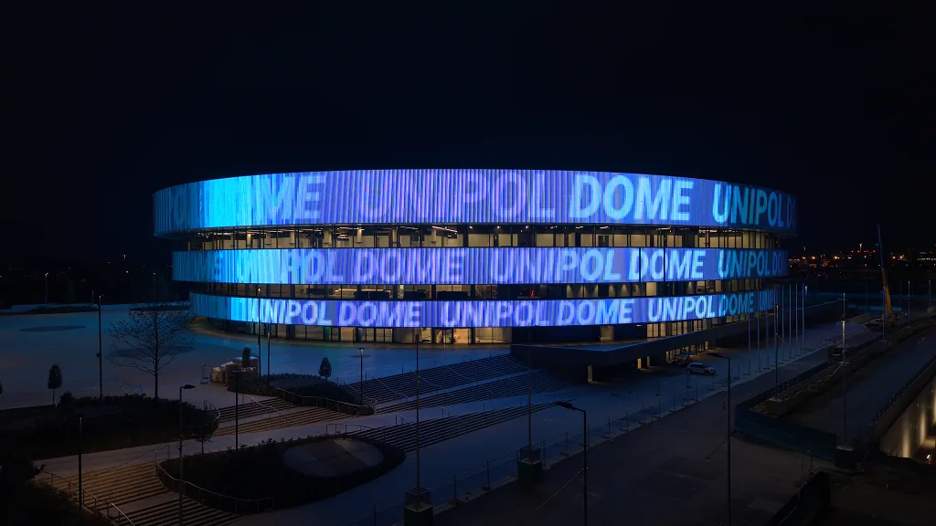 The arena façade lit blue reading UNIPOL DOME across the rings