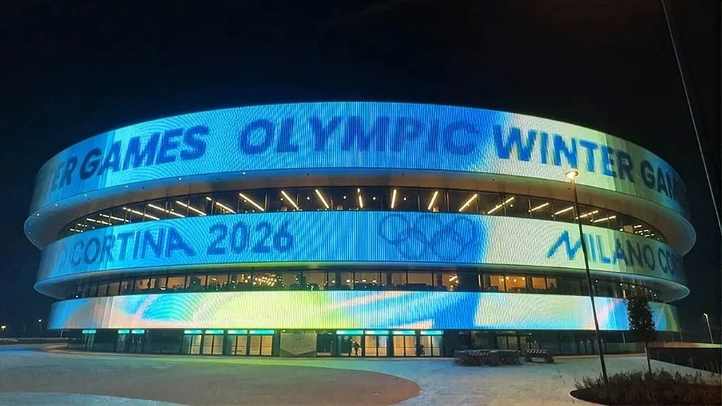 The façade lit blue with text running right around the three rings
