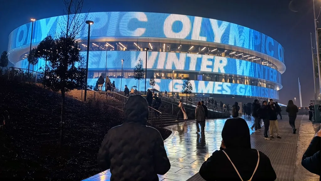 Spectators walking toward the blue-lit arena in the evening