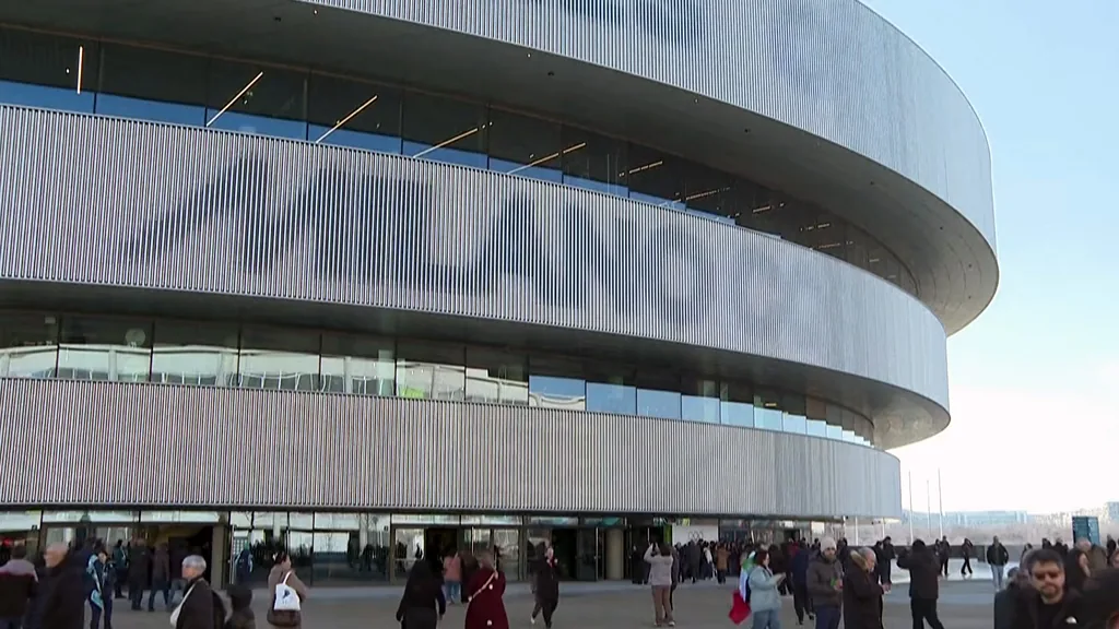 The arena and its aluminium façade by day with crowds arriving