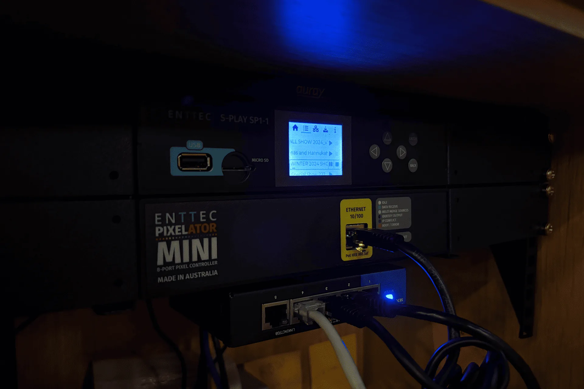 An ENTTEC Pixelator Mini mounted behind the artwork, status LEDs lit, data cables patched in
