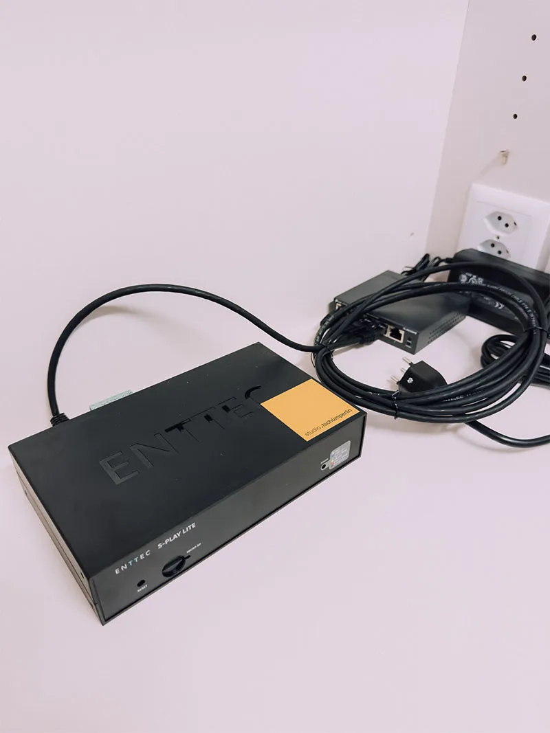 白墙前完成布线的黑色 ENTTEC 灯光秀控制器,网线与电源线盘绕在四周