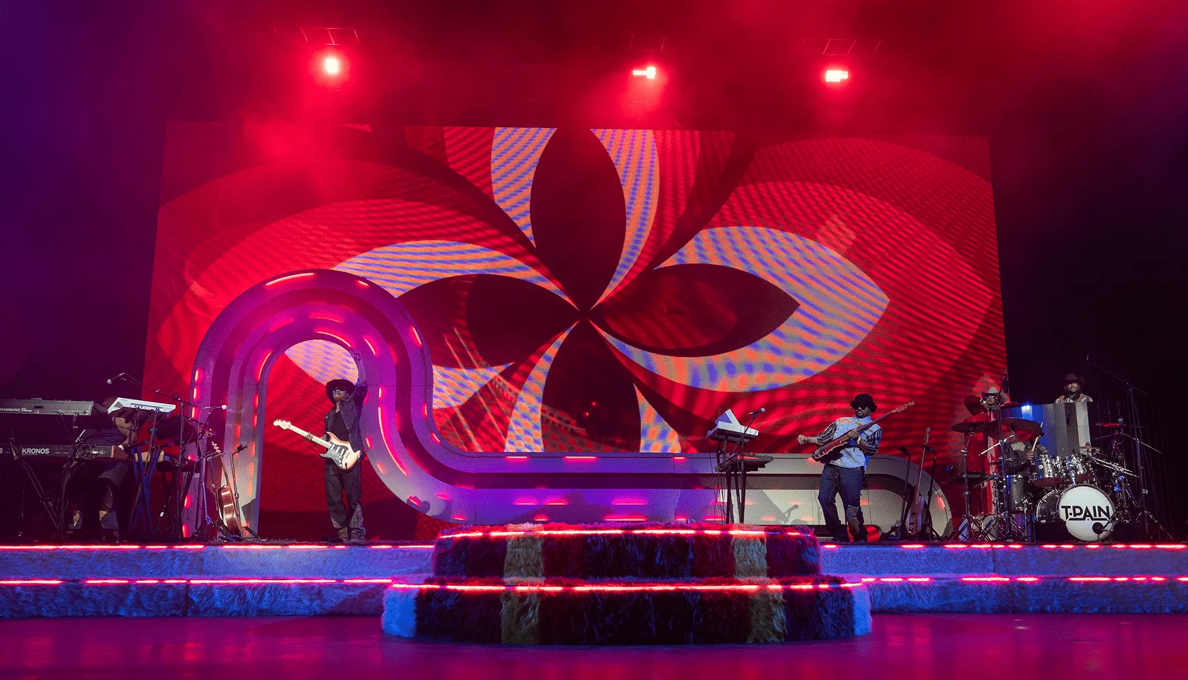 The band mid-set, the arch curving away to the left in front of a spinning pinwheel graphic on the video wall