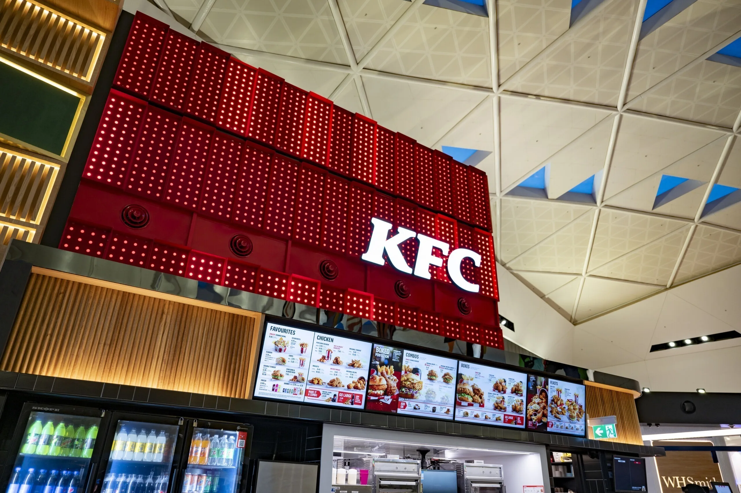 灯盒亮在数字菜单屏与饮料柜上方，天花上是三角形天窗