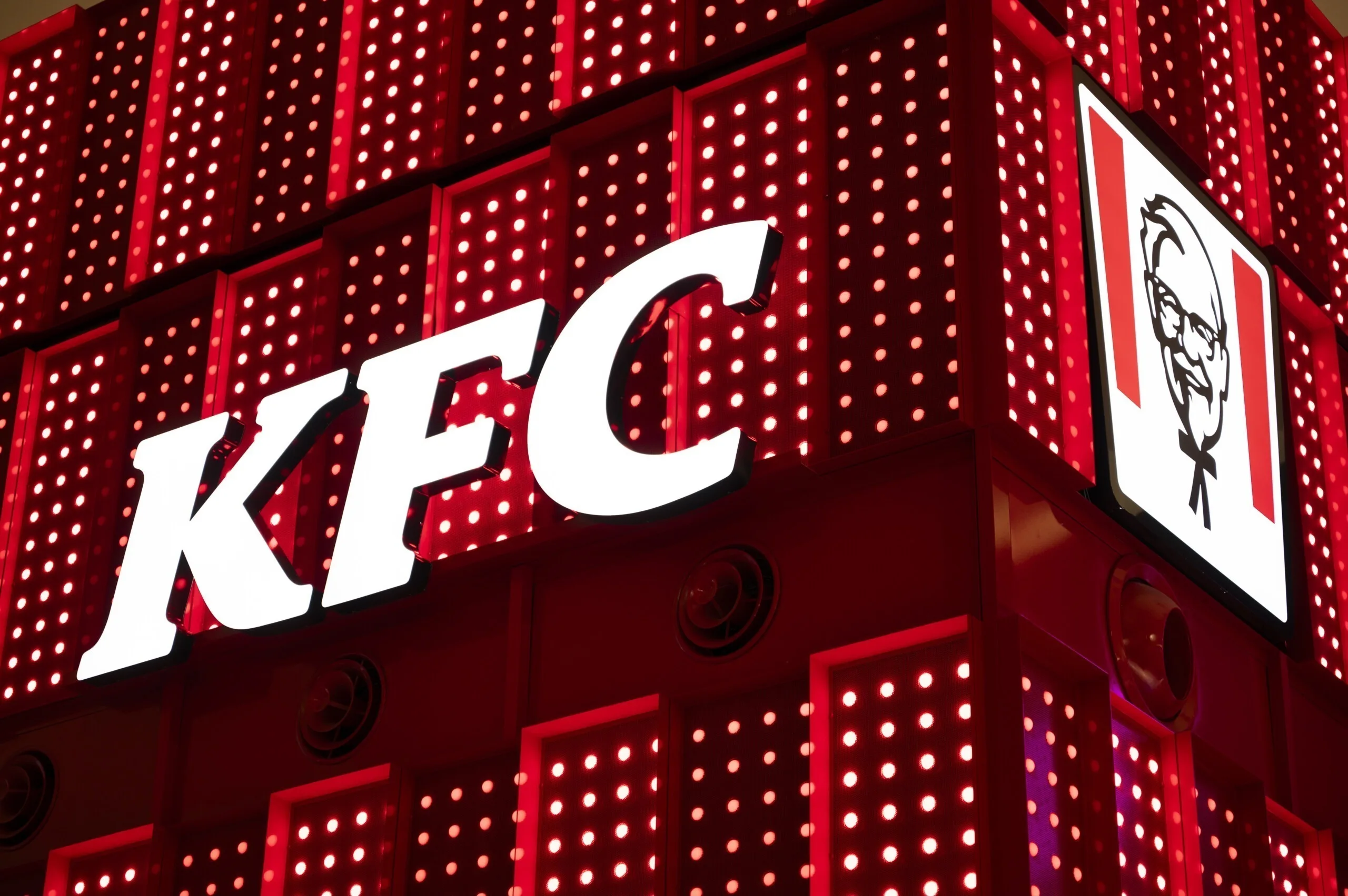 转角的紧凑构图，一面是白色 KFC 字标，另一面是标识图案面板