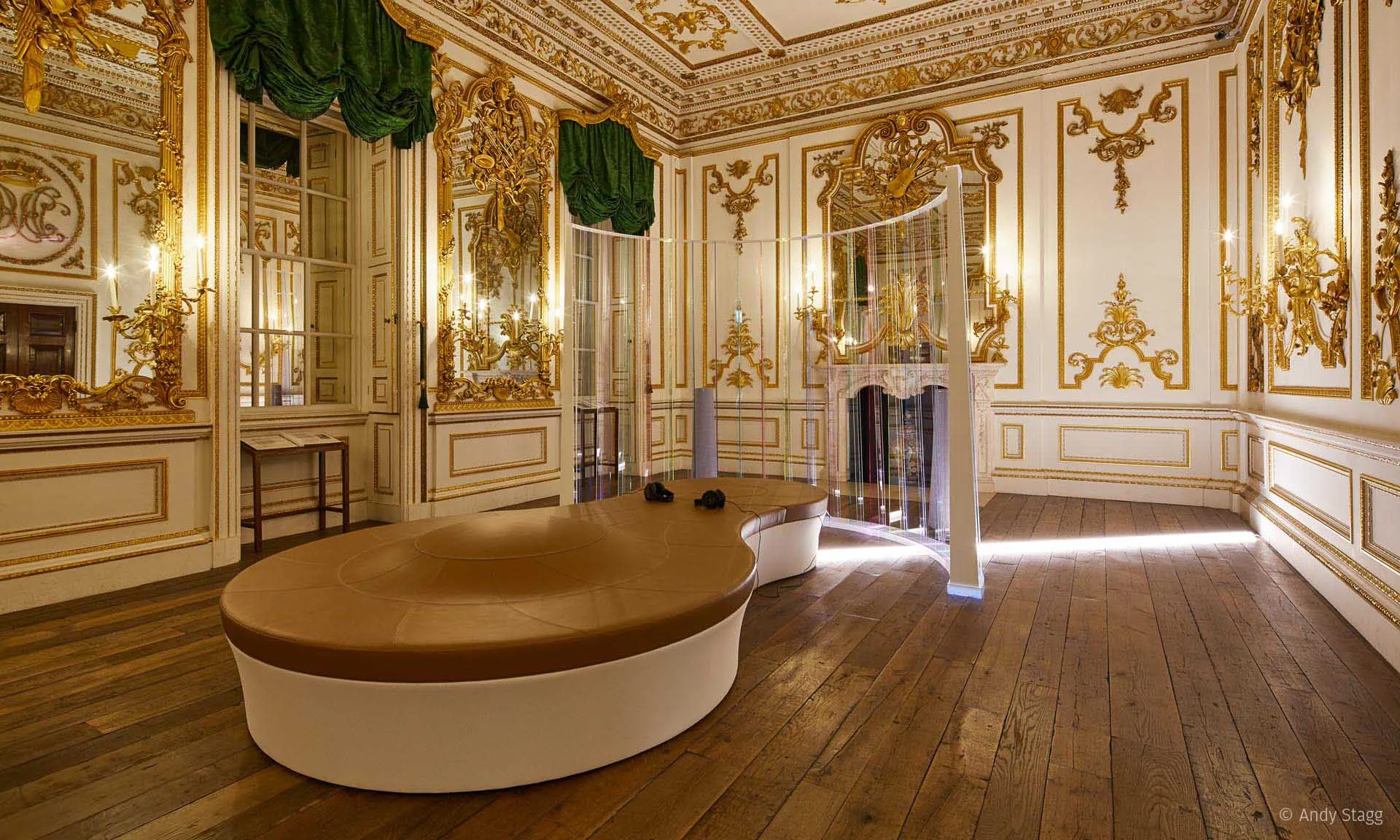 从长边方向看 Norfolk House Music Room，中央是一张弧形浅褐长椅，点亮的屏体环绕在其远端