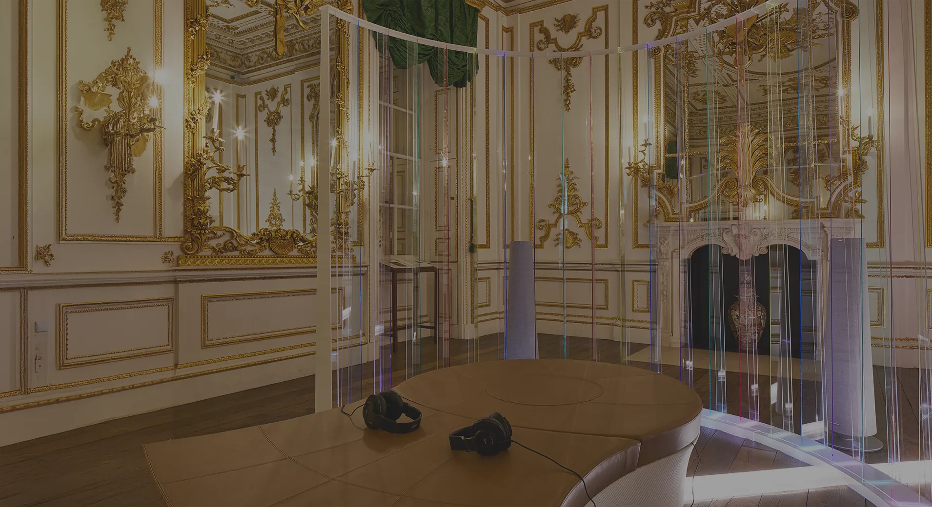 位于镀金的 Norfolk House Music Room 内的 Memory and Light 装置，弧形亚克力屏环绕着一处圆形平台，平台上放着耳机